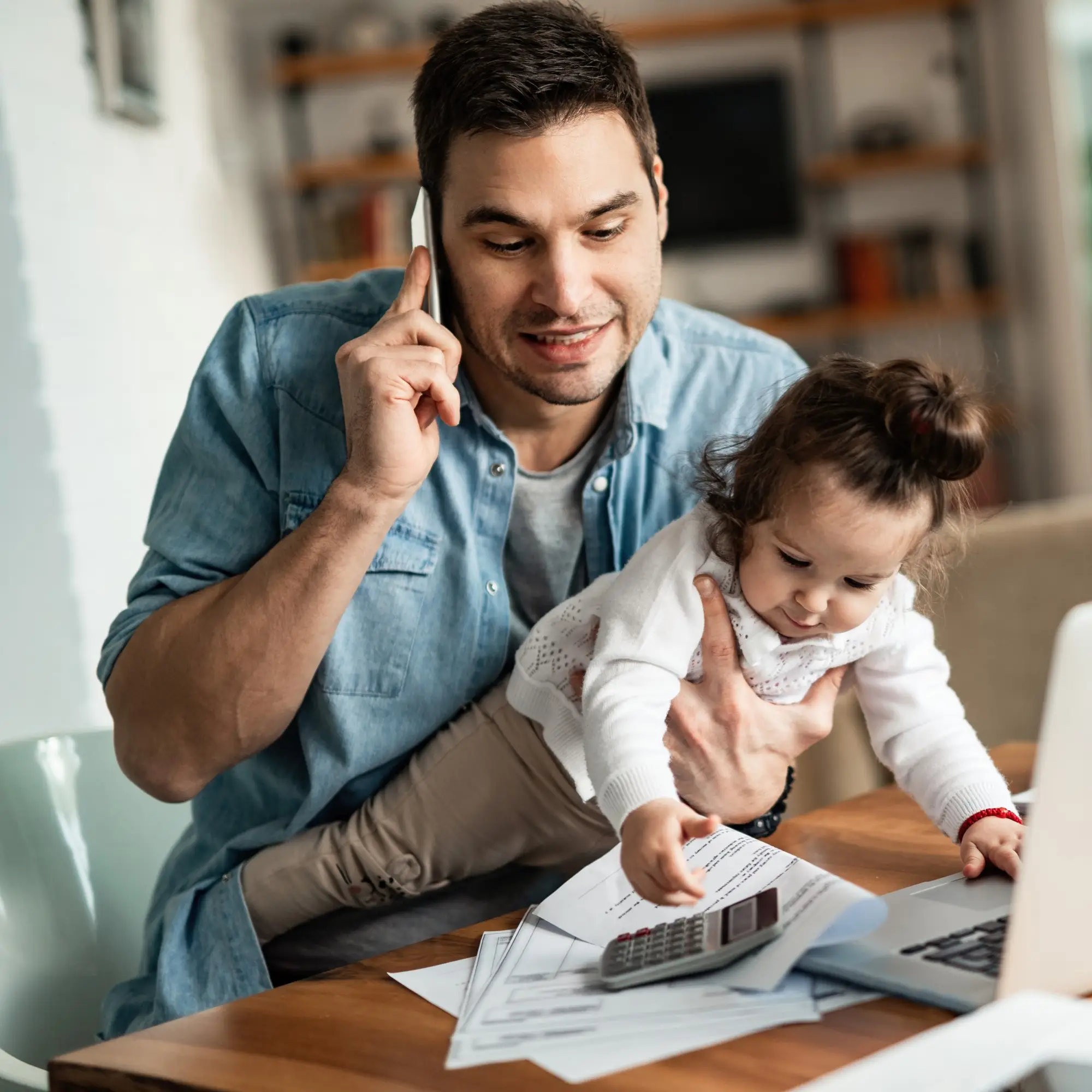 Working From Home Dad On Phone Whilst Holding His Child