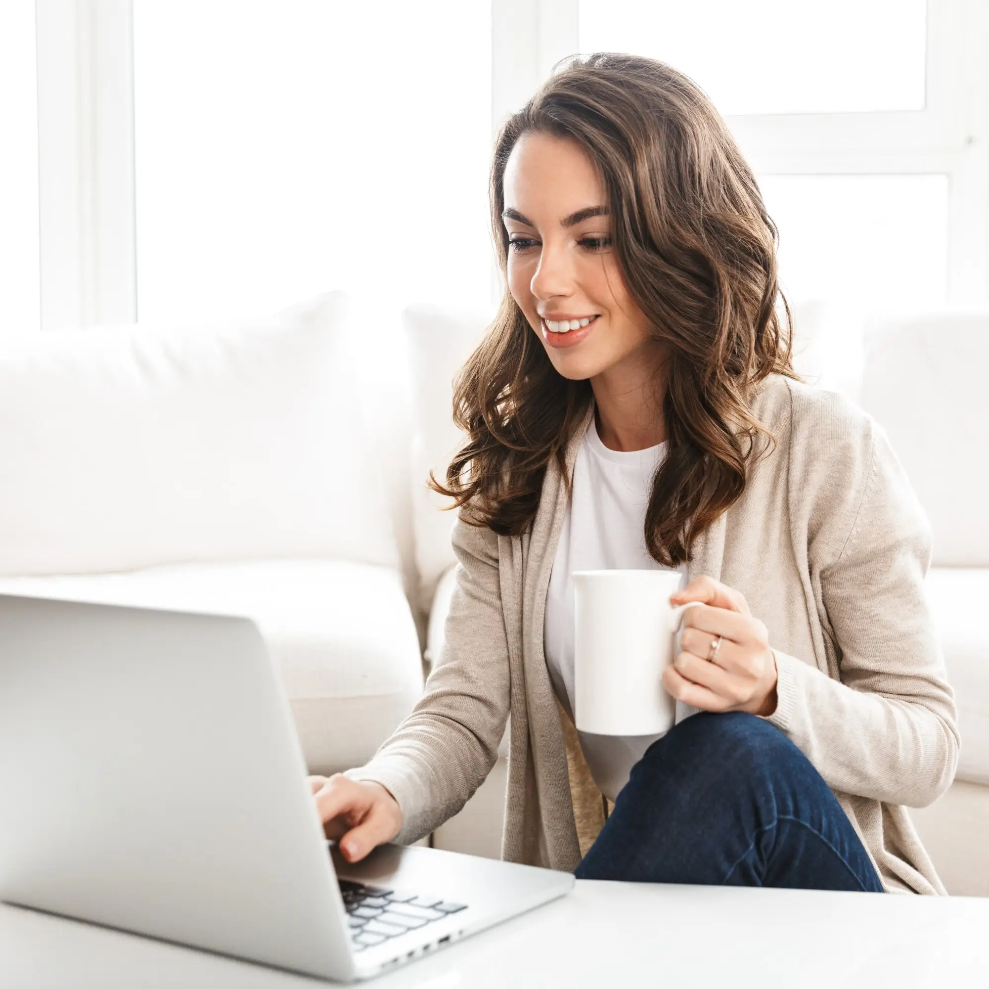 Young Woman Smiling Whilst Browsing On A Laptop
